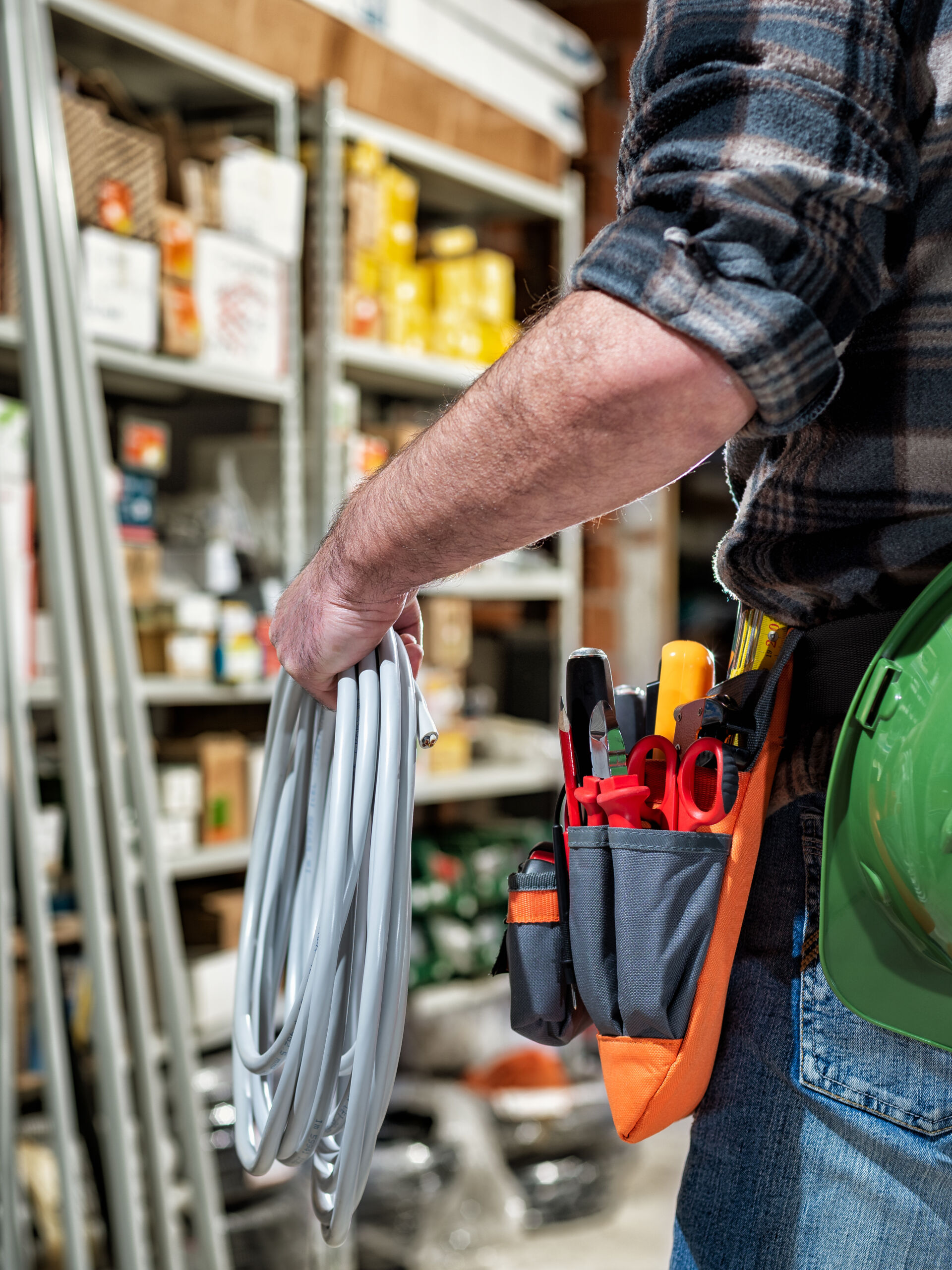 Electrician in the electrical parts store is holding the roll of electrical cable. Construction industry, electrical system.